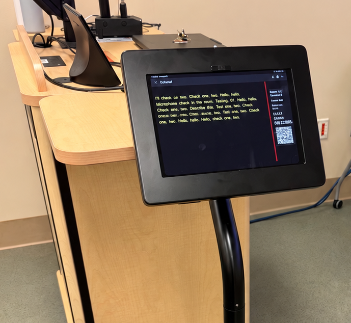 Ipad stand in front of classroom lectern displays captions and QR code..